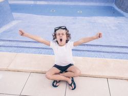 Child in snorkel goggles yawning on poolside
