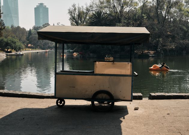 Empty vendor cart next to pond in city park