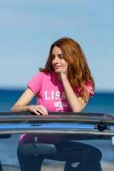 Smiling woman leaning on roof of car