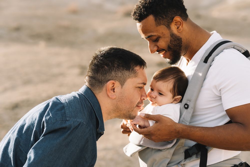 Unrecognizable diverse men walking with baby on nature