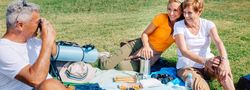 Wide shot of man taking photo of his wife and daughter on scenic picnic