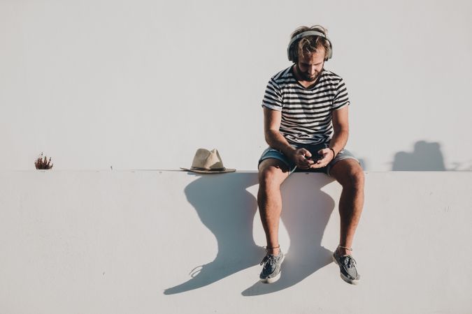 Young male sitting with smartphone and headphones