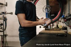 Worker cleaning his hands after repairing bicycle in workshop bxG3X4