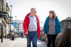 Older man and woman walking together on sidewalk