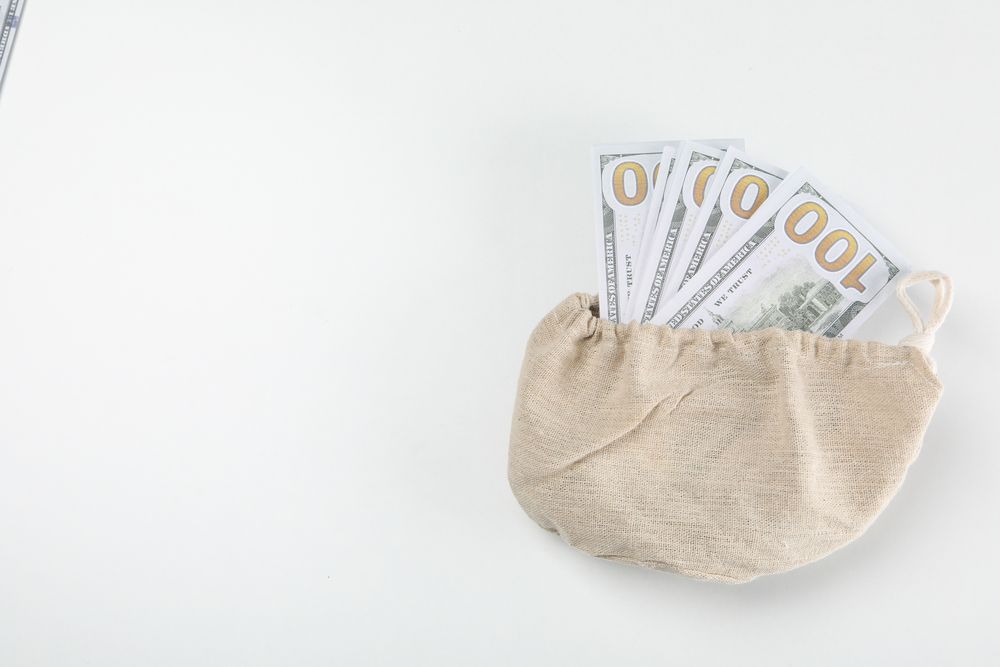 A bundle of 100 bucks in a bag on a light background.