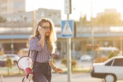 Woman walking outside speaking on phone with megaphone dressed in checkered shirt