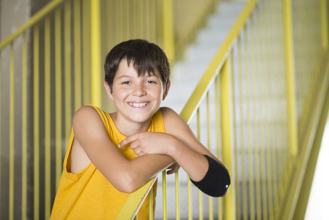 Smiling teenage boy in yellow shirt standing on staircase