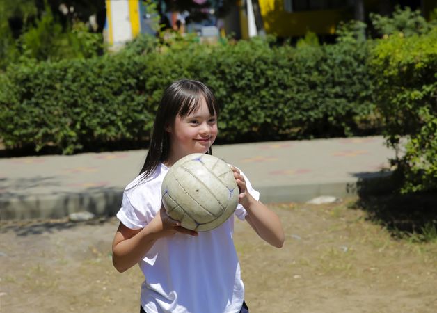 Playful child holding volleyball outdoors