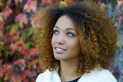 Portrait of wistful woman looking up with fall leaves in background