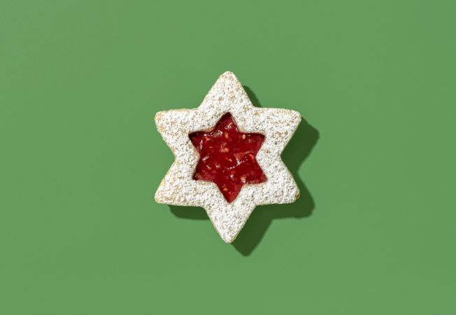 Linzer cookie with raspberry jam above view on green background