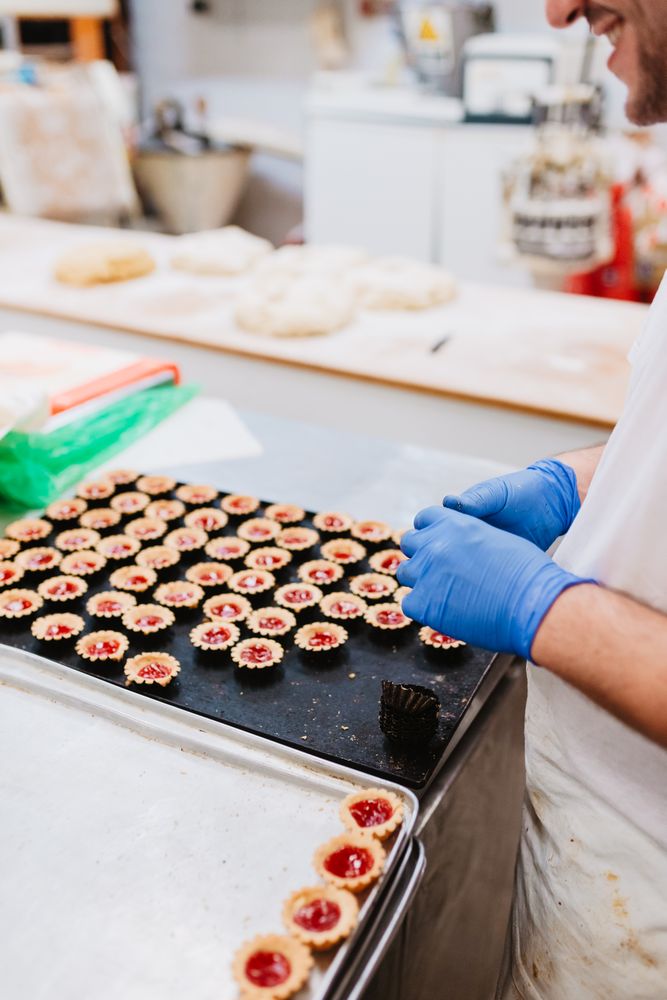 Anonymous baker decorating small cakes