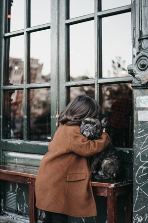 Girl hugging sad dog on city street