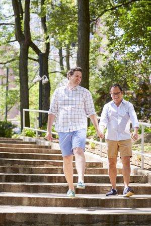 Two men holding hands and getting down outdoor staircase