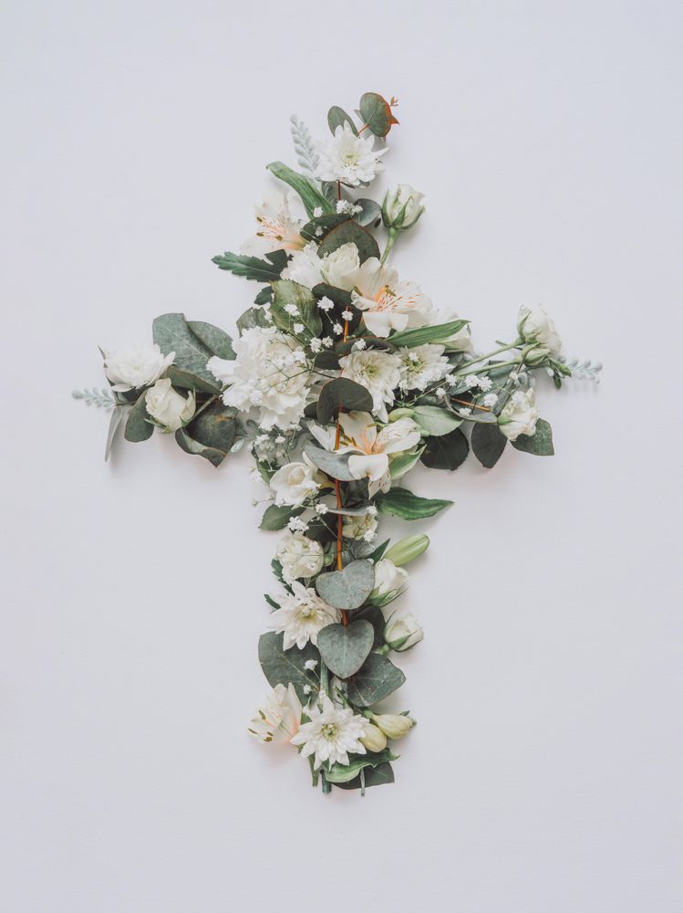 Easter layout with flowers and leaves in cross shape on light paper background