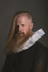 Confident adult red haired medieval magnate looking away