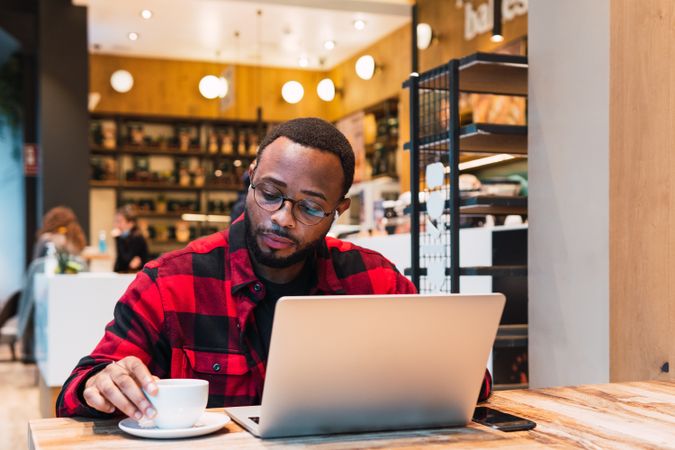 Smiling Black man working on laptop in cafe