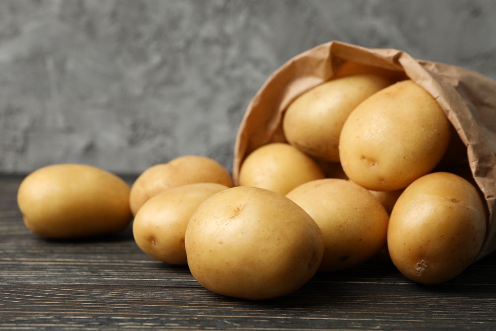 Paper bag with potatoes in grey room