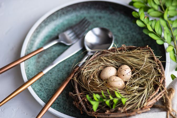 Easter table setting with nest and mini eggs, on blue plate with silverware