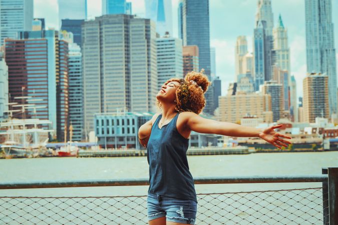 Black woman with her arms open with Hudson River in the background, copy space