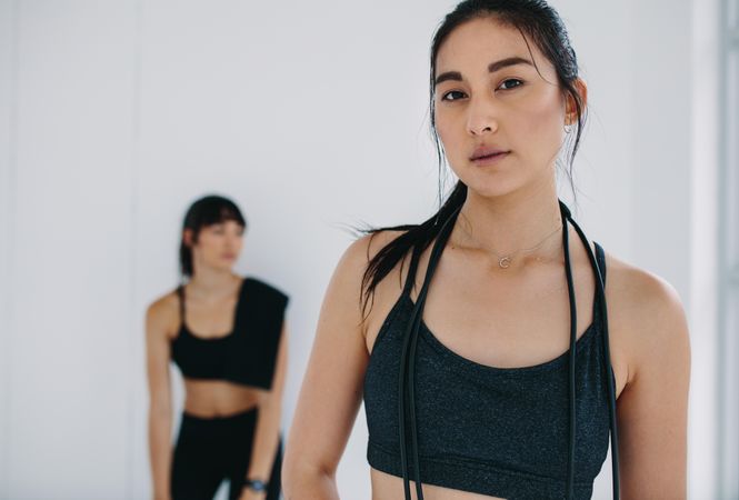Close up portrait of fitness woman with jump ropes around her neck with friend in background