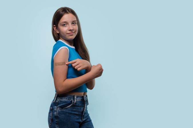 Girl pointing to bandage on arm after vaccination