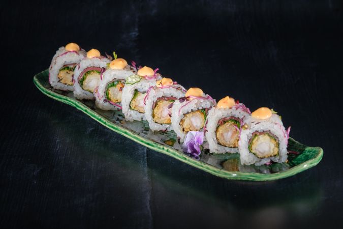 Appetizing uramaki rolls served with sauce on marble tray