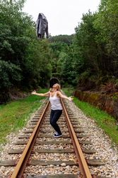 Woman walking along railway though greenery part of road