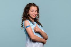 Girl giving thumbs up after receiving vaccine