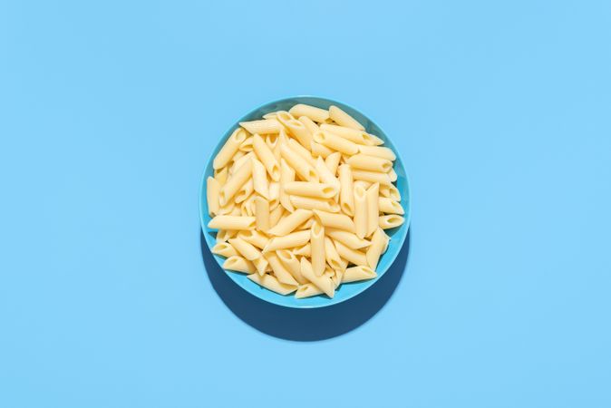 Penne pasta top view isolated on a blue background