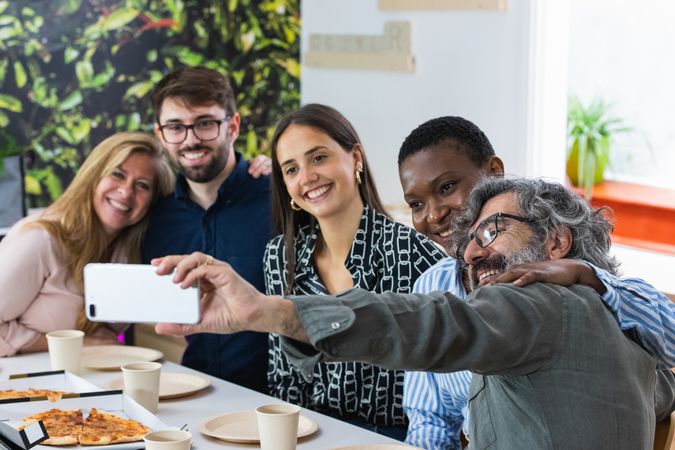 Cheerful multiethnic friends taking selfie during lunch