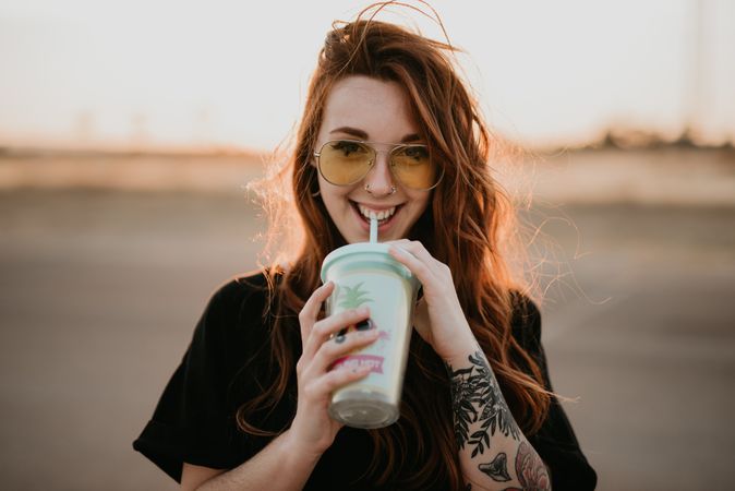 Long haired smiling woman drinking milkshake and looking at camera