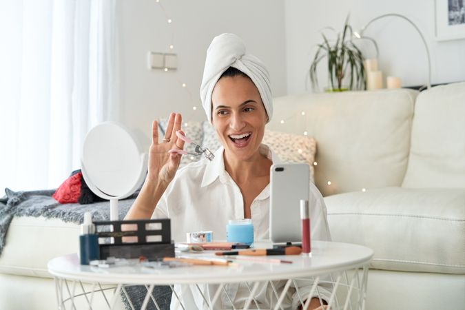 Cheerful woman doing makeup with eyelash curler
