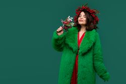 Woman in green coat and red berry wreath