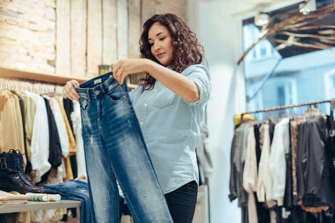 Woman looking at pair of jeans in a fashion store