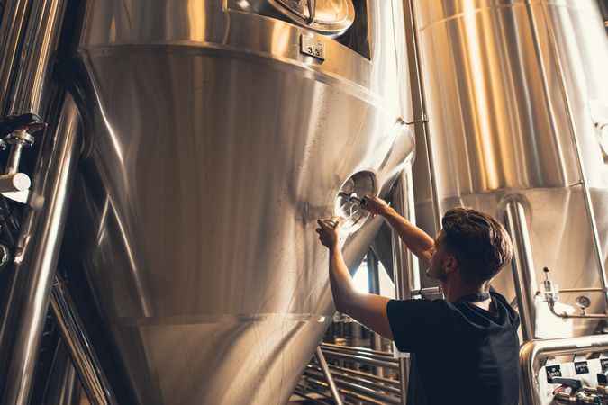 Male brewer checking temperature of beer tank