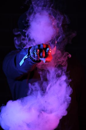 Unrecognizable man surrounded by smoke in neon lighting