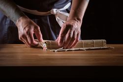 Male shushi man hands preparing different pieces of makis