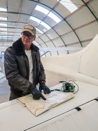Pilot with map beside small plane