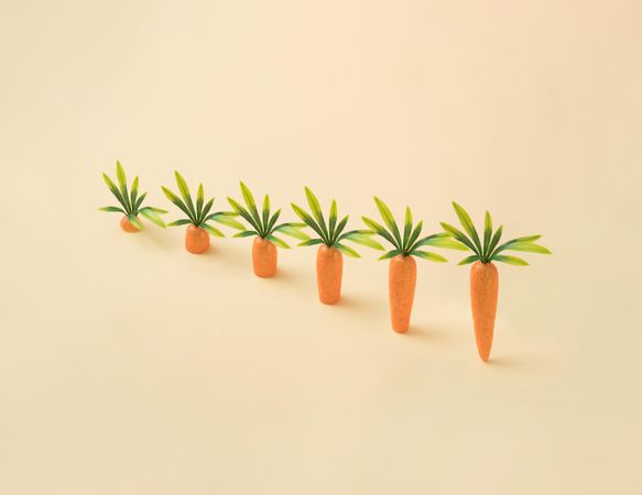 Row of carrots on pastel yellow background
