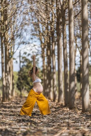 Concentrated adult expectant mother practicing yoga in park