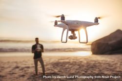 Young man on the seashore flying a drone 4M32a0