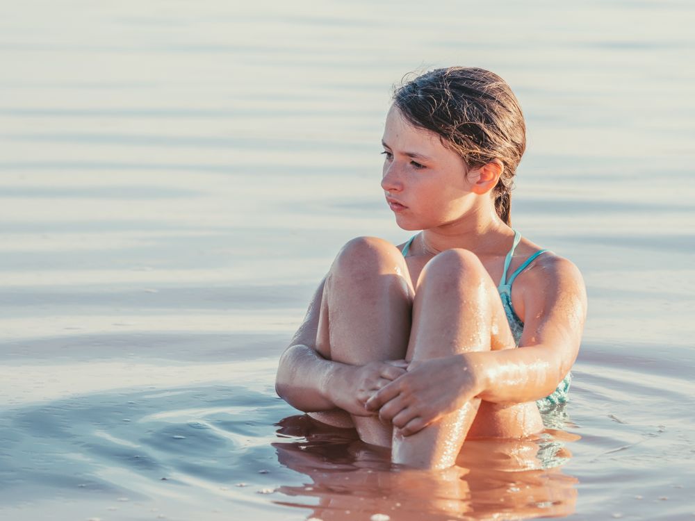Teenage girl sitting in fresh water in sunny day