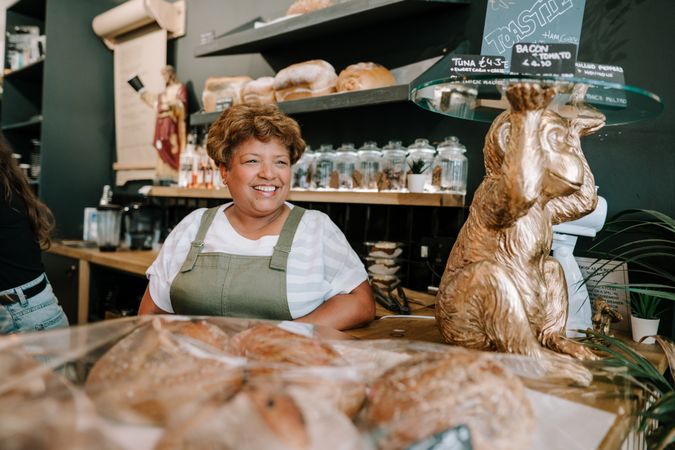 Older Black woman behind pastries at cafe counter