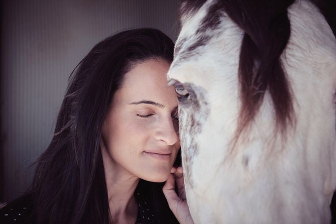 Tender woman caressing white horse
