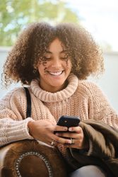 Cheerful Black woman using smartphone