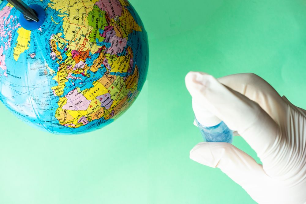 Covid-19 virus concept of hands in latex gloves spraying globe