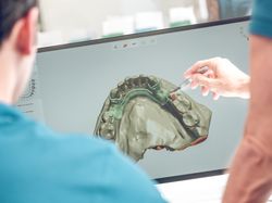 Dentist pointing at monitor with jaw model