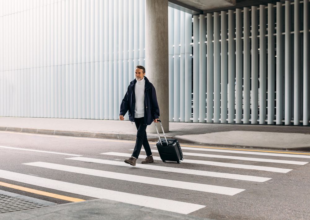 Older man with suitcase on crosswalk
