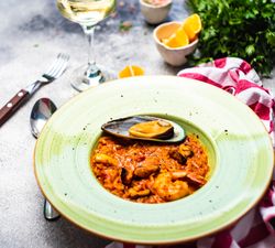 Risotto with sea food in green bowl with lemon slices