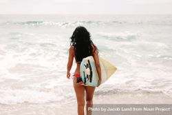 Rear view of woman in bikini with surfboard walking toward sea 5rq7M0